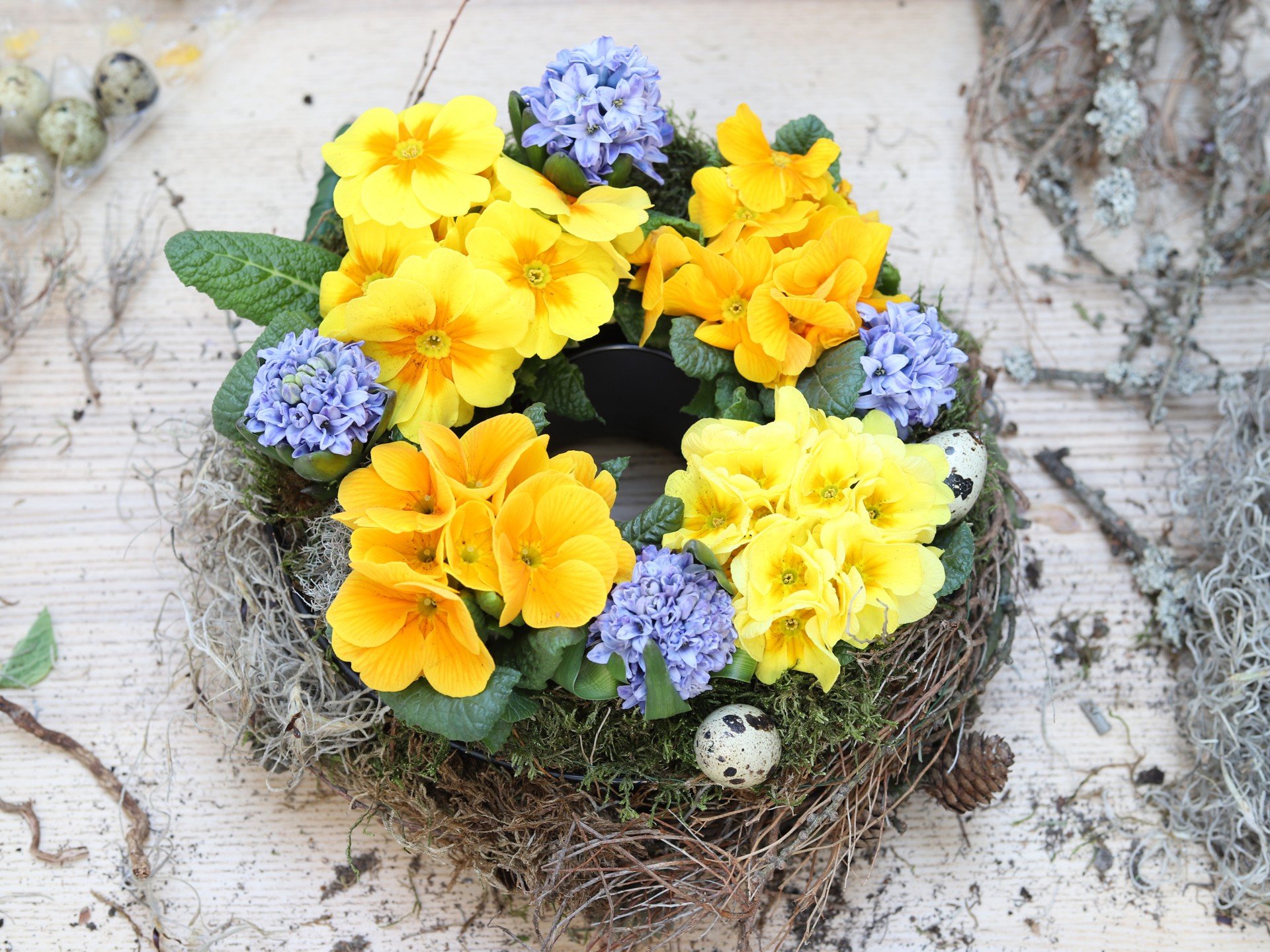 Krāsains galda vainags no pavasara augiem podiņos.